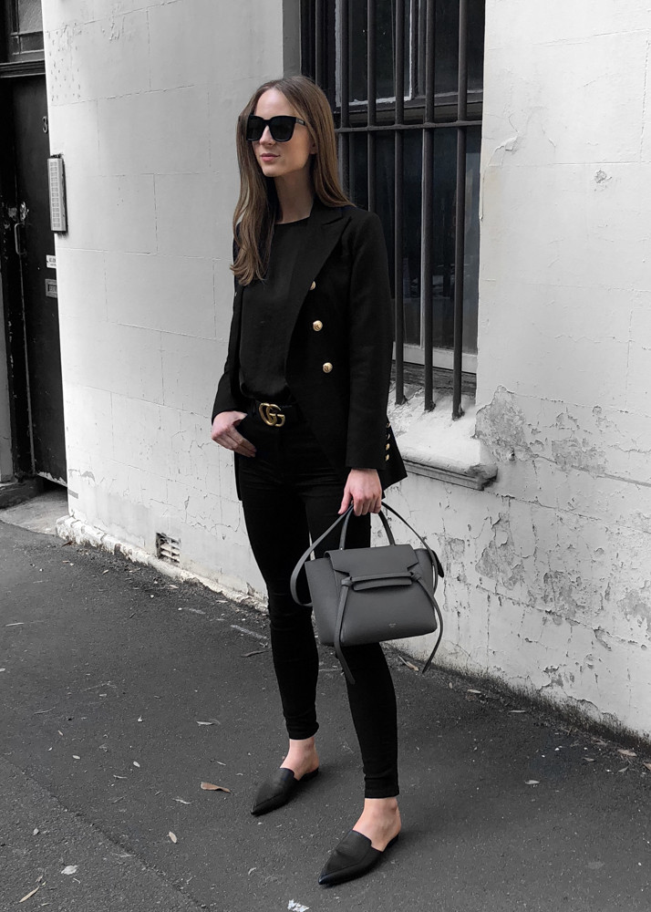 A guest wears a light grey dress and a black Gucci belt bag